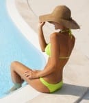 Beautiful young woman sitting by swimming-pool